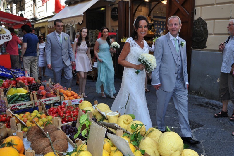 bride and groom walk in front of fruit stand in Sorrento, Italy | Planner: Venice Events | via https://emmalinebride.com/real-weddings/italian-weddings-destination/