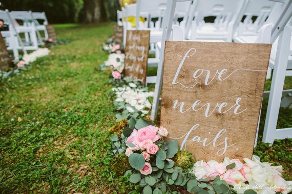 Love never fails ceremony aisle signs by Paper and Pine Co | via Wood Themed Wedding Ideas: https://emmalinebride.com/themes/wood-themed-wedding-ideas/