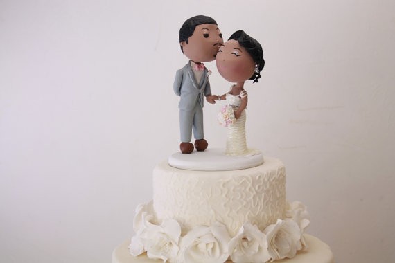 groom kisses bride on cheek cake topper | figurine cake toppers that look like you | by artifice producciones | https://emmalinebride.com/reception/figurine-cake-toppers/