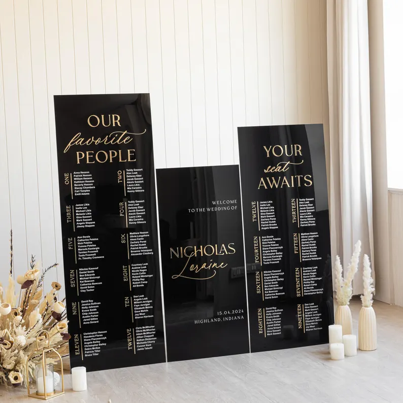 acrylic wedding seating chart with black background and gold and white lettering