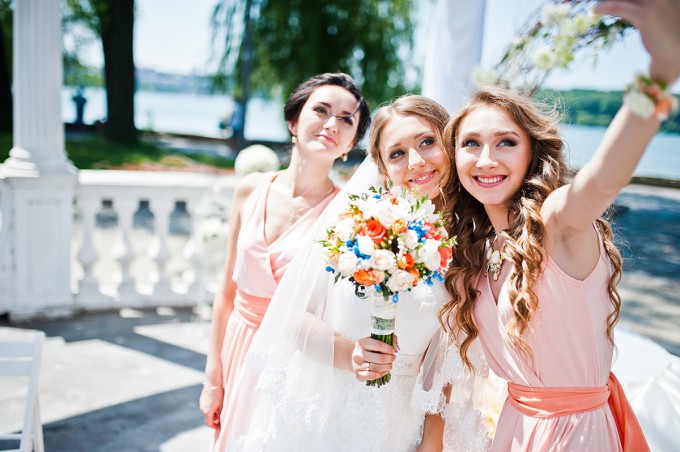 bride with bridesmaid at wedding ceremony doing selfie