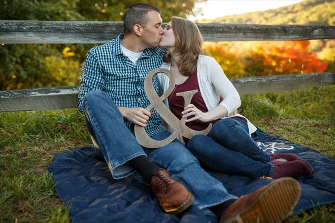 couple kiss with & monogram sign during engagement session| engagement photography by Butler Photography LLC.| Love Fall Weddings? See this Somers, CT Engagement Session - https://emmalinebride.com/real-weddings/love-the-fall-weddings-see-this-somers-ct-engagement-session/