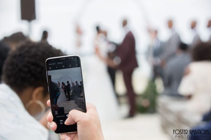 photo of a guest taking a photo on their phone at the ceremony