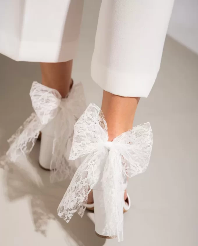 bridal bow made of lace on back of white leather sandals with heel