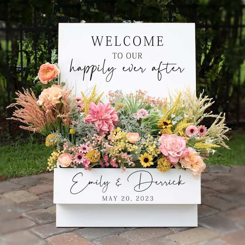 Welcome sign for wedding with flower box in the front filled with fresh flowers