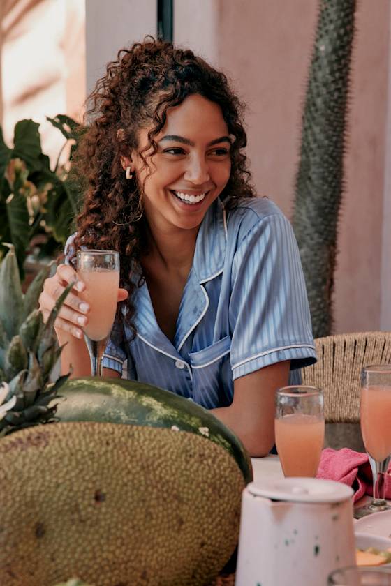 bridesmaid in striped pajamas drinking a mimosa getting ready