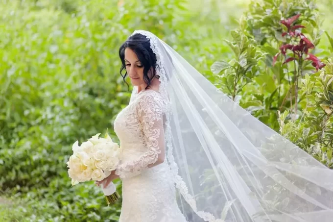 bride wearing floral lace mantilla veil with long sleeve lace wedding gown