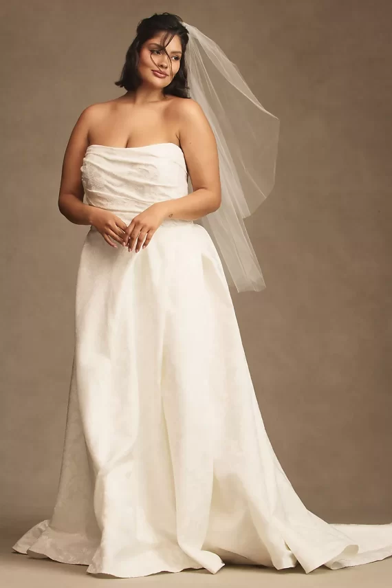 A-line wedding dress with strapless neckline worn on bride with veil