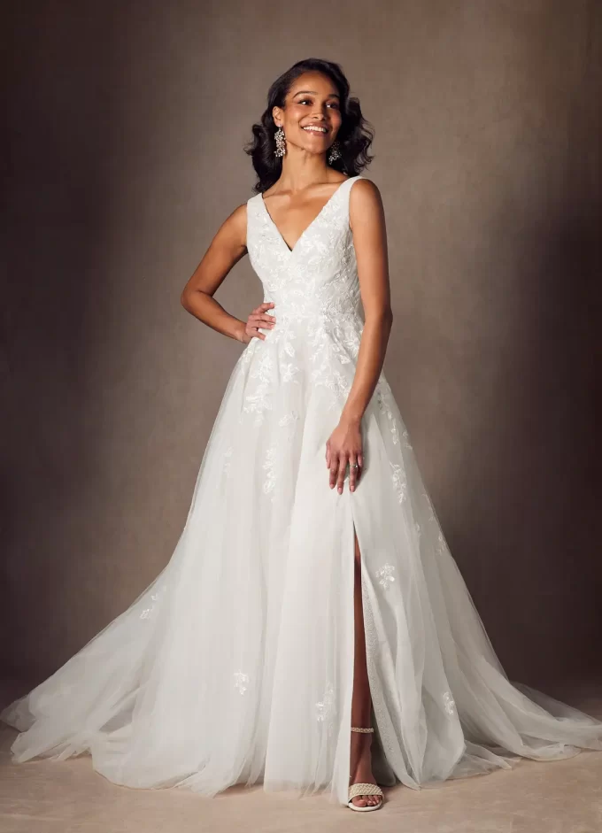 Bride wearing a v-neck a-line wedding dress with tulle and sequins and chapel length train