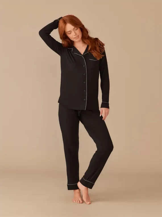 Woman wearing long sleeve and pants style black pajamas with button down the front