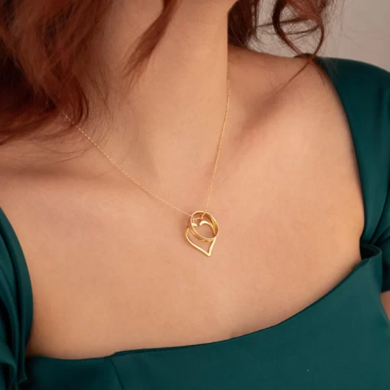 Gold closed-heart ring holder necklace holding an engagement ring