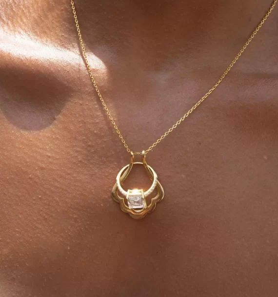 Seashell-shaped ring holder necklace holding an engagement ring