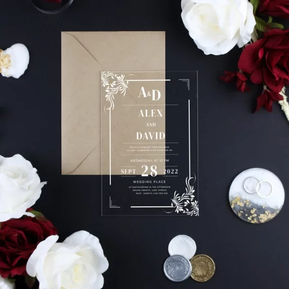 Modern clear acrylic wedding invitation with gold foil text on a white background