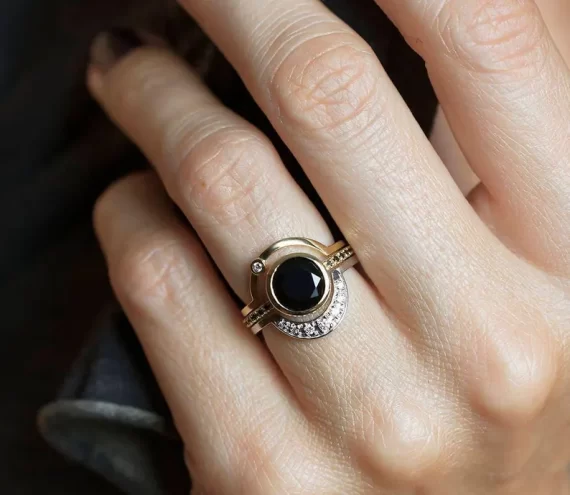 Modern black diamond engagement ring worn on hand with eclipse design