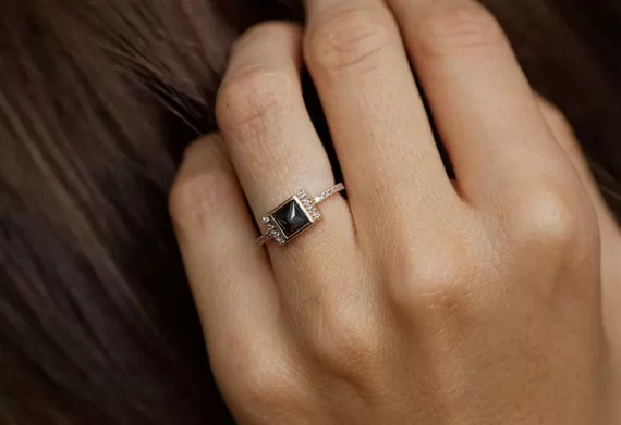 Princess cut black diamond engagement ring shown on hand