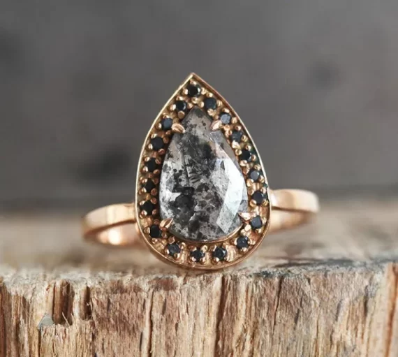 Teardrop salt and pepper black diamond engagement ring worn on finger