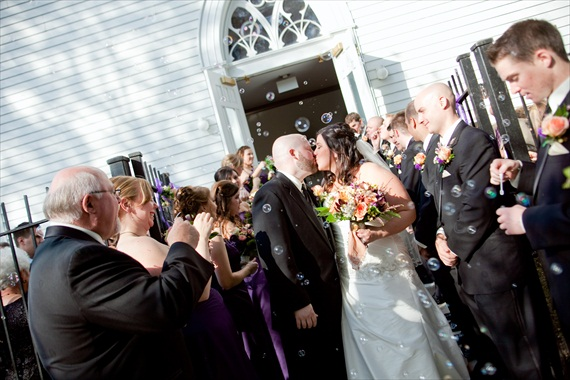 Wedding guests using bubble guns to blow bubbles as the couple exits the ceremony