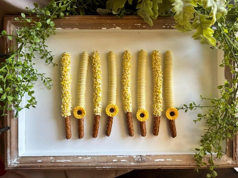Sunflower adorned chocolate covered pretzel wedding favors displayed on a tray for favors table