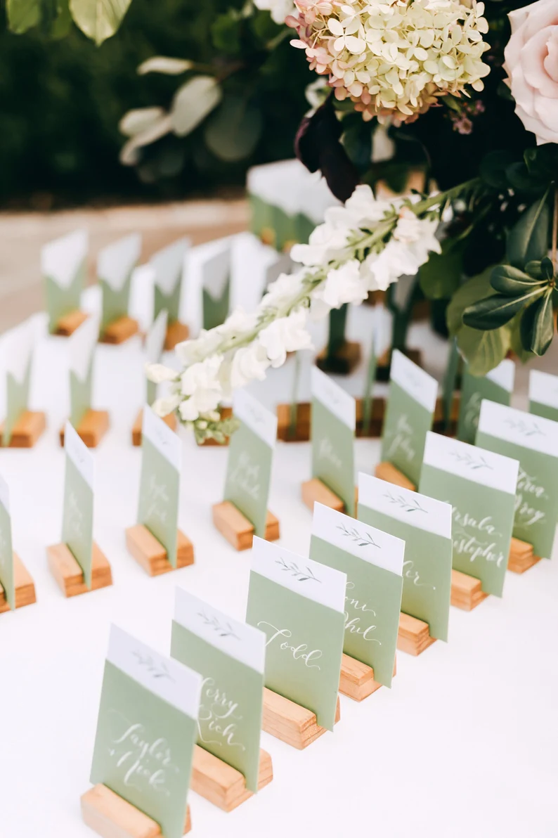 Elegant wooden wedding place card holders on a beautifully set reception table with flowers and candles