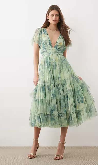 guest wearing deep v-neck beach wedding guest dress with flutter sleeves, midi length for seaside celebration