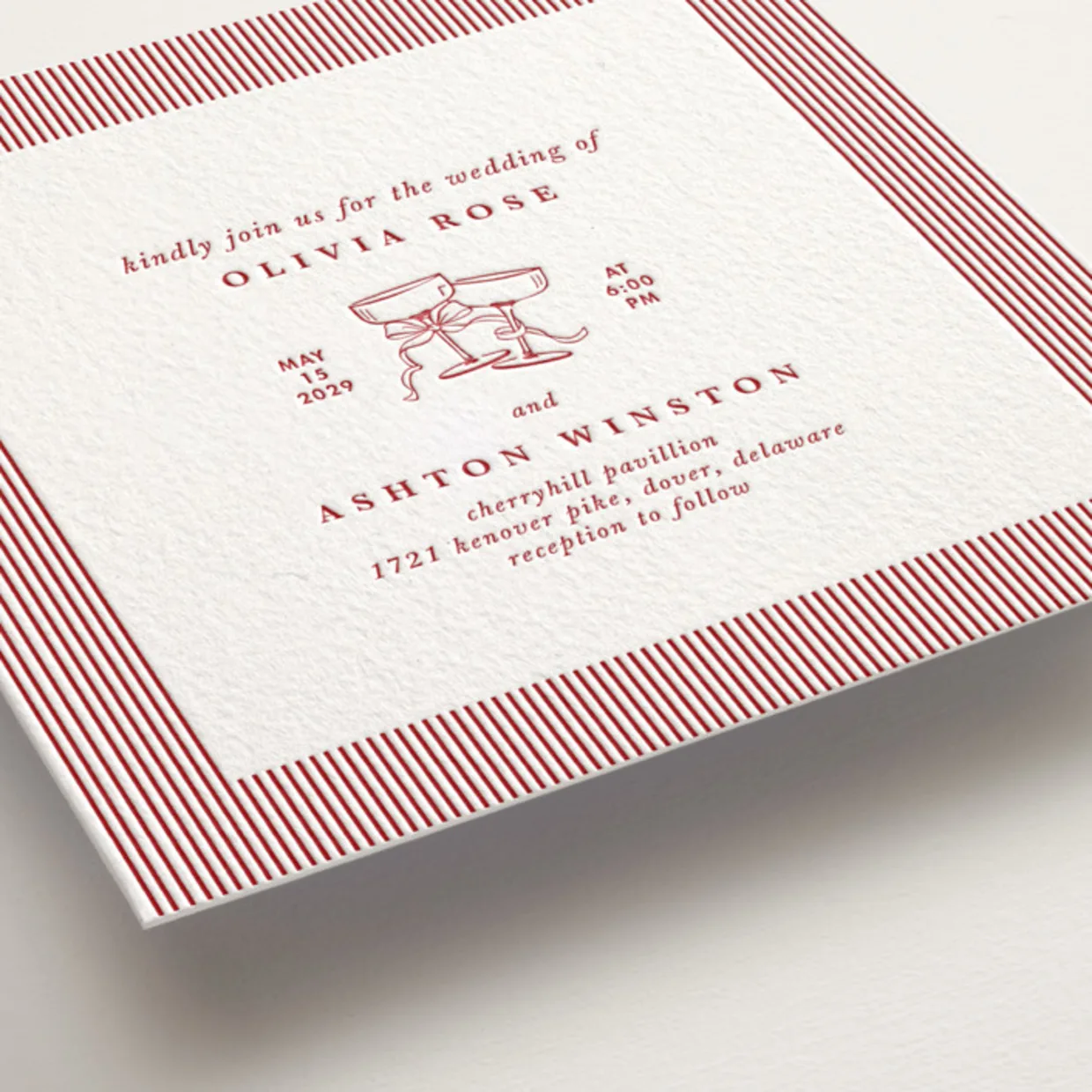 letterpress luxury wedding invitation with red stripes and champagne coup flutes