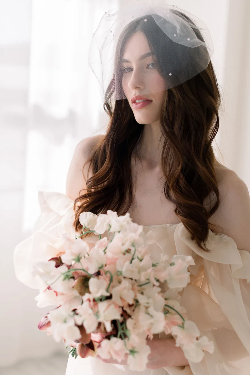 bride wearing elegant barely there tulle wedding veil holding bouquet of flowers