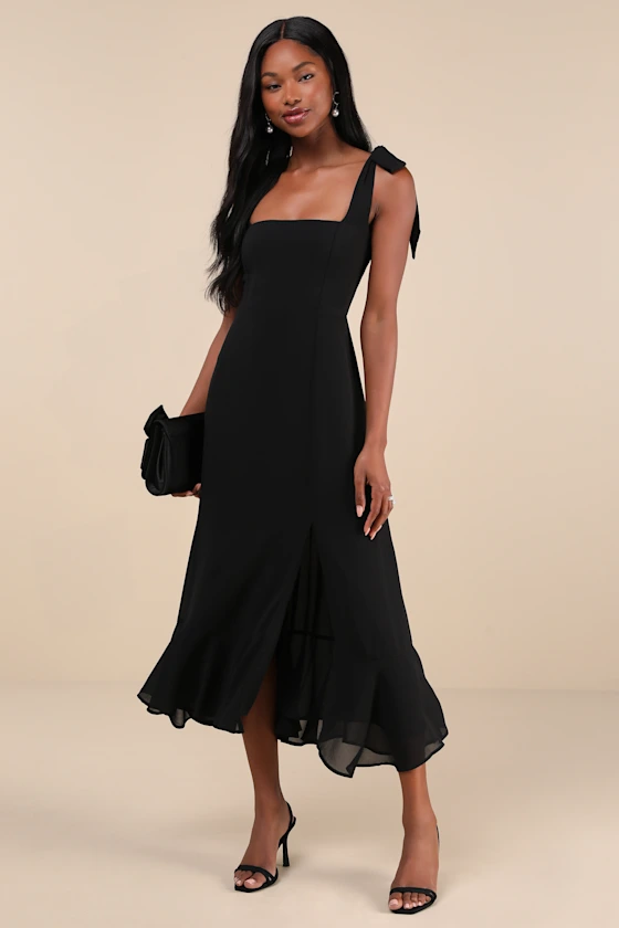 wedding guest wearing black midi length dress with ties at shoulder