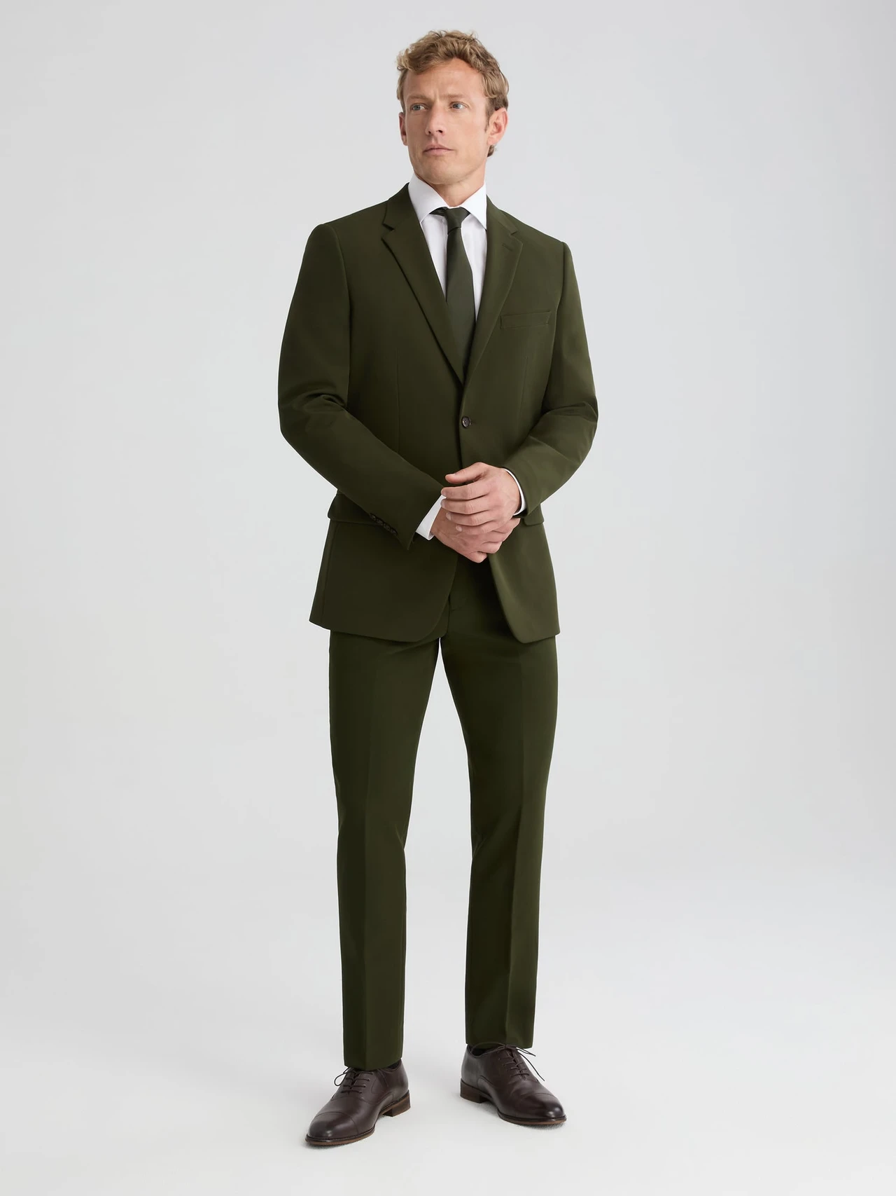 groom wearing dark olive green suit with tie and dress pants
