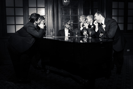 fun photo of groom playing piano surrounded by groomsmen - photo: Daniel Fugaciu Photography | via https://emmalinebride.com