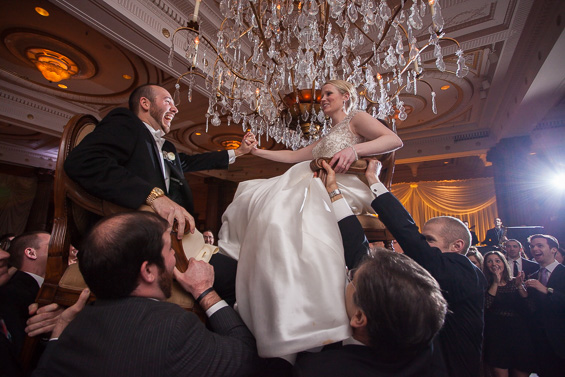 bride and groom hoisted up in chairs at wedding reception - photo: Daniel Fugaciu Photography | via https://emmalinebride.com
