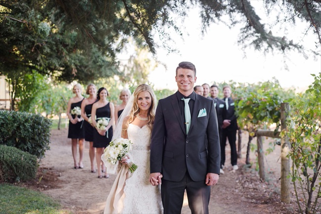 bride and groom in front of wedding party, bridesmaids wearing one-shoulder black dresses