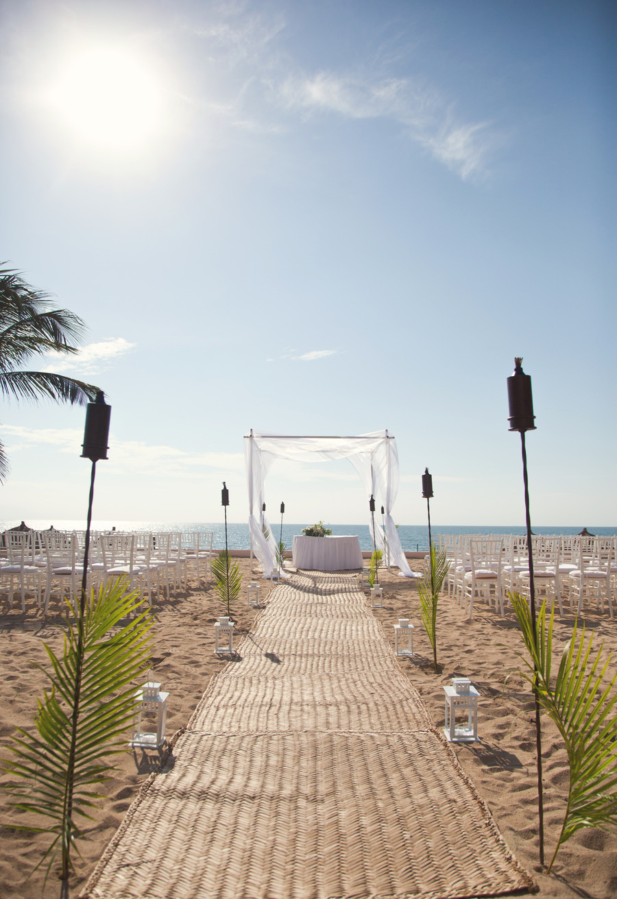 aisle with mat lined with tiki torches and white lanterns for beach ceremony | photo: victoria anne | via decorate for beach wedding ideas from emmalinebride.com