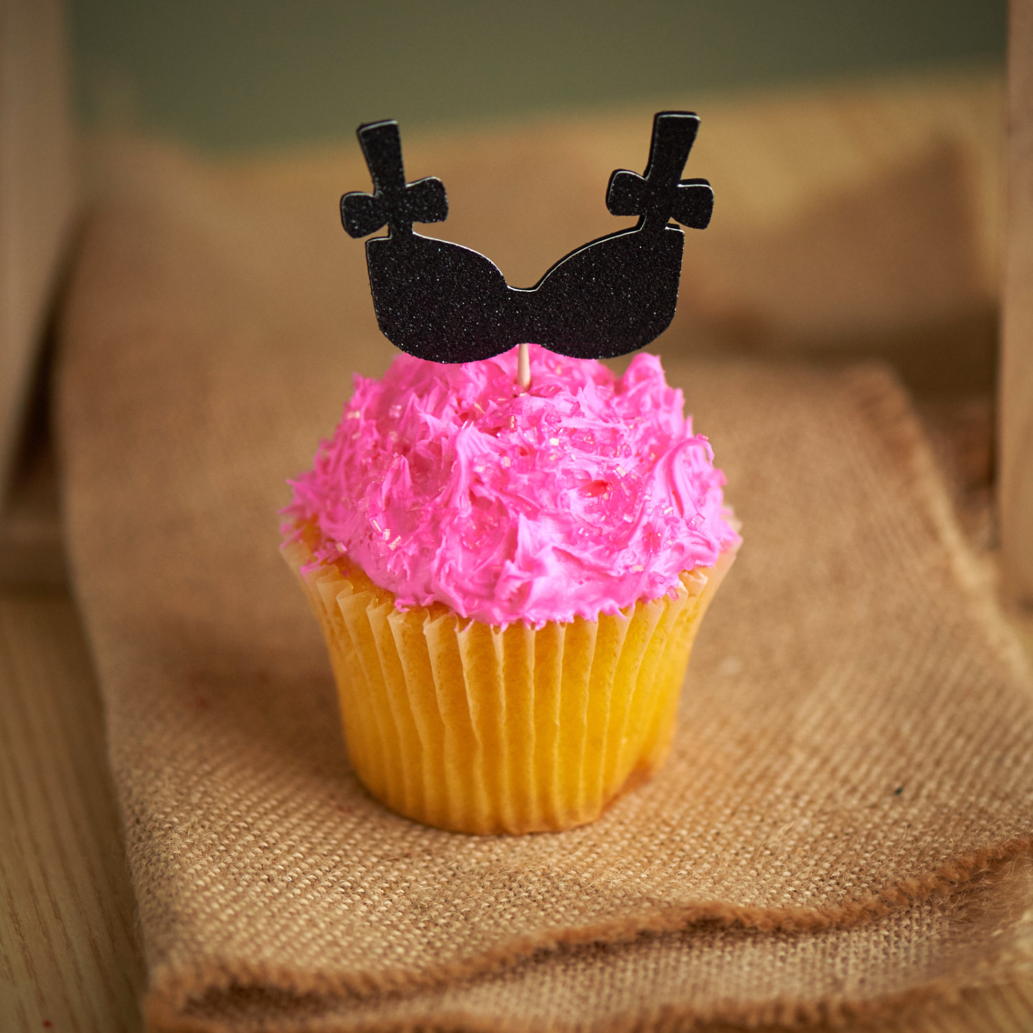 black bra cupcake toppers on hot pink cupcake by confetti momma party | fun bachelorette party ideas | https://emmalinebride.com/planning/fun-bachelorette-party-ideas/