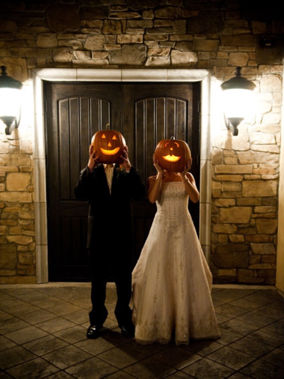 bride and groom holding pumpkins in front of faces halloween wedding