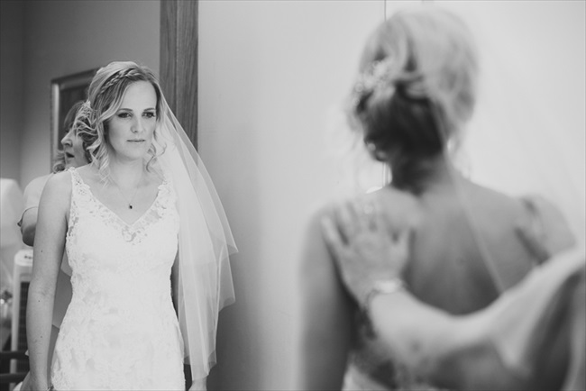 The bride looks in the mirror before the ceremony | Photo: Searching for the Light Photography LLC | via https://emmalinebride.com/real-weddings/colorado-chic-wedding-kendall-brian/