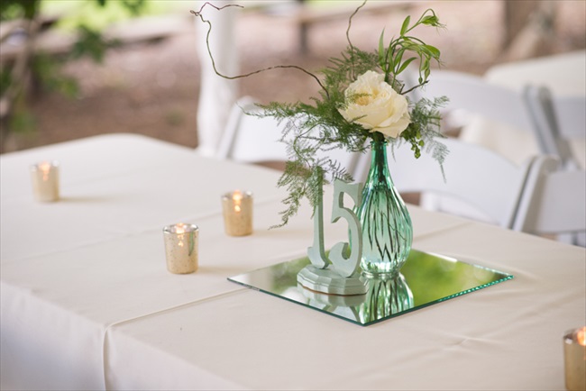 Easy DIY centerpiece idea:  a table number atop a mirror, white linens, a vase of flowers, and chic votive candles | Photo: Searching for the Light Photography LLC | via https://emmalinebride.com/real-weddings/colorado-chic-wedding-kendall-brian/