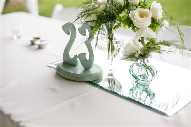 Table number and mirror with vase of flowers for centerpiece | Photo: Searching for the Light Photography LLC | via https://emmalinebride.com/real-weddings/colorado-chic-wedding-kendall-brian/