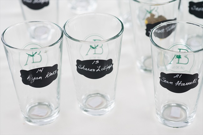 Guests were greeted with escort glasses instead of cards;  the glasses had chalkboard paint with their name and table number already written on it.  Brilliant idea! | Photo: Searching for the Light Photography LLC | via https://emmalinebride.com/real-weddings/colorado-chic-wedding-kendall-brian/