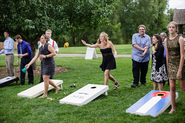 Guests played cornhole as entertainment before dinner | Photo: Searching for the Light Photography LLC | via https://emmalinebride.com/real-weddings/colorado-chic-wedding-kendall-brian/