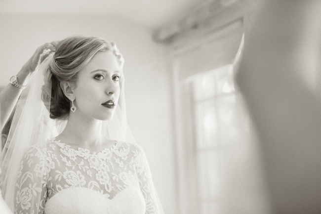 bride getting ready while looking in mirror at Connecticut waterfront wedding - photo: Melani Lust Photography | via https://emmalinebride.com