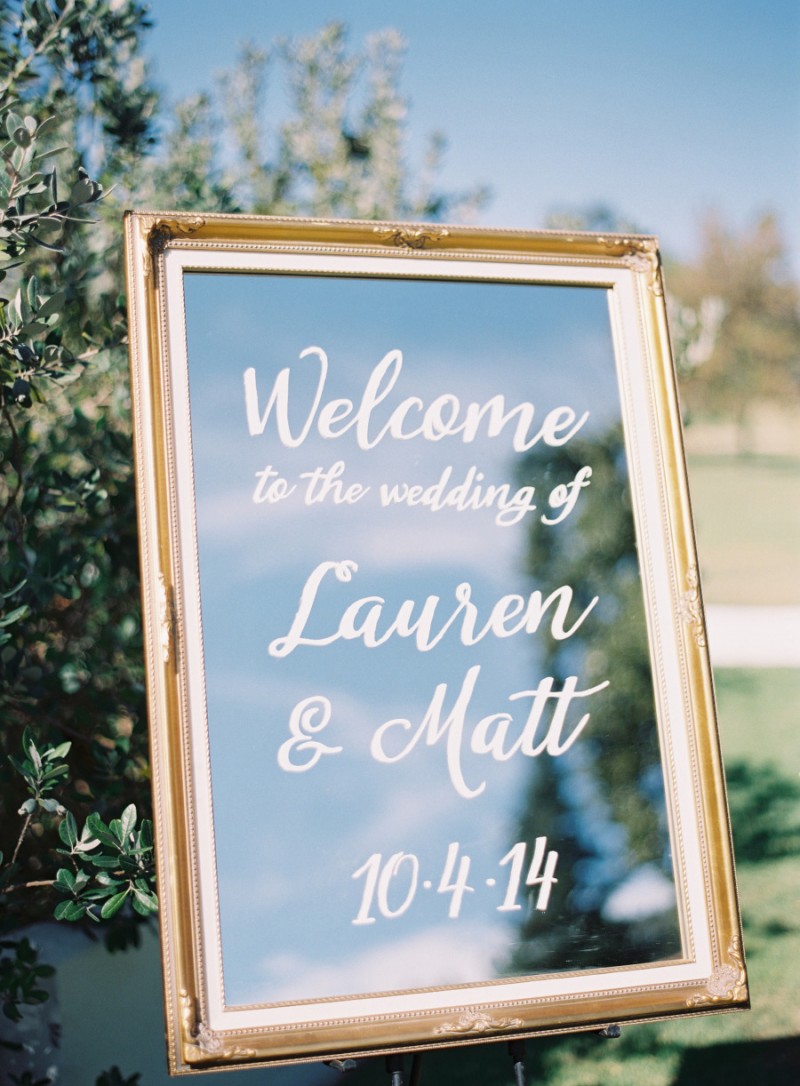 Use a mirror and paint to welcome guests to your wedding.  Photo: Rylee Hitchner | https://emmalinebride.com/decor/wedding-mirror-signs/